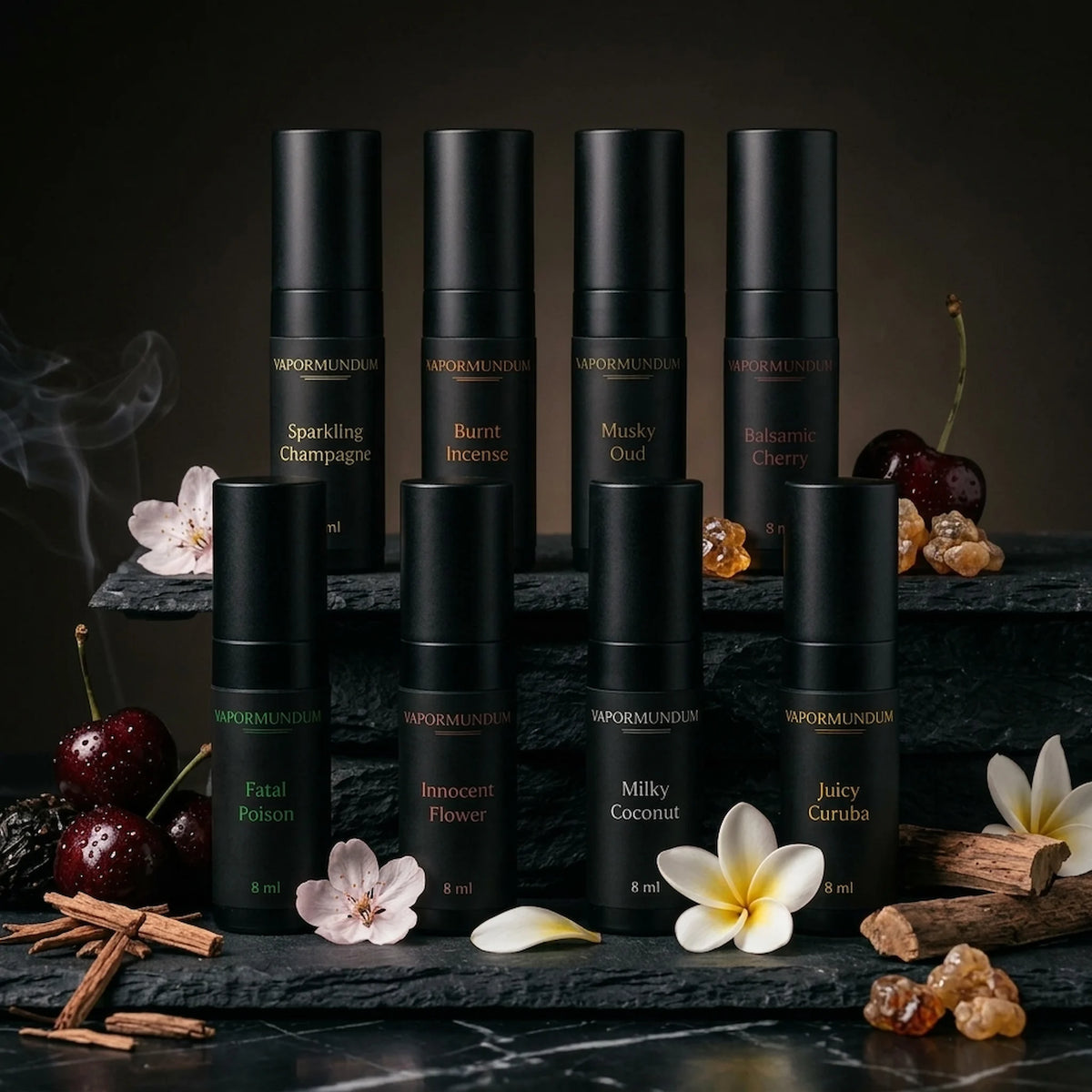 vapormundum complete collection of eight 8ml layering accords and fragrance boosters in matte black travel spray atomizers arranged on layered dark slate with botanical ingredients, raw resins, and cherries