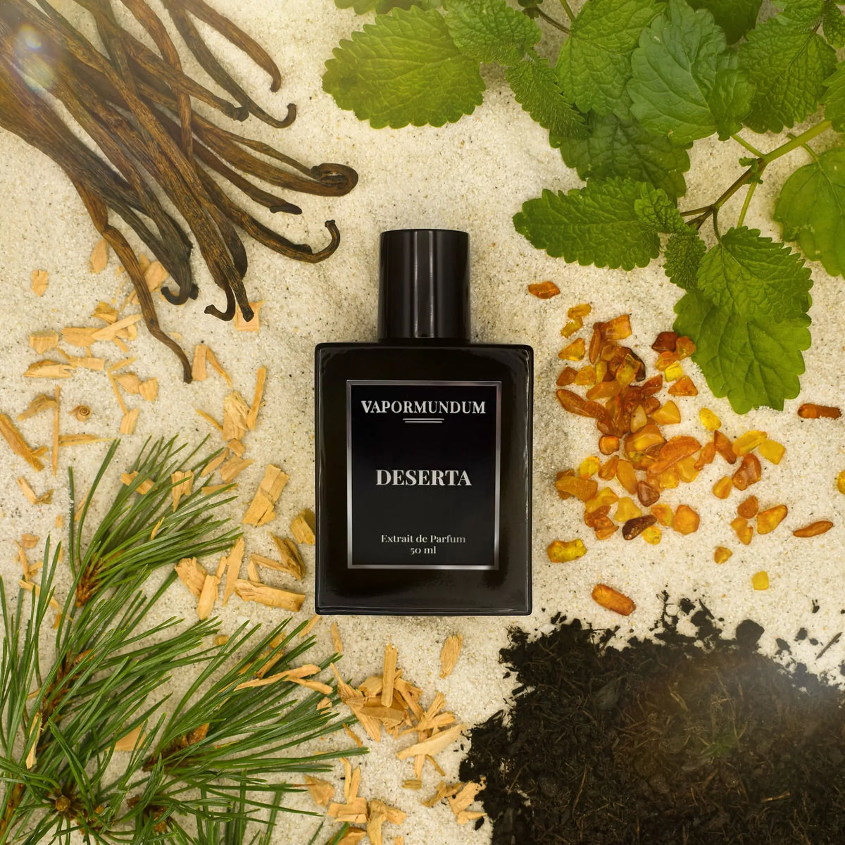 VAPORMUNDUM DESERTA Extrait de Parfum luxury black bottle surrounded by desert sand, vanilla beans, amber resin, and botanical ingredients